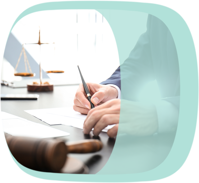 Eine Person im Anzug notiert etwas. Auf dem Schreibtisch befindet sich ein Richterhammer und eine Waage