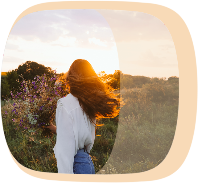 Eine frau läuft mit einem Blumenstrauß in der Hand auf einer Wiese dem Sonnenuntergang entgegen