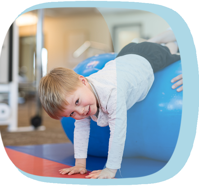 Ein kleiner Junge liegt quer auf einem Ball