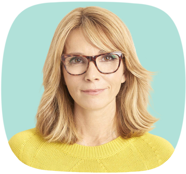 Eine blonde Frau mit Brille lächelt sanft in die Kamera