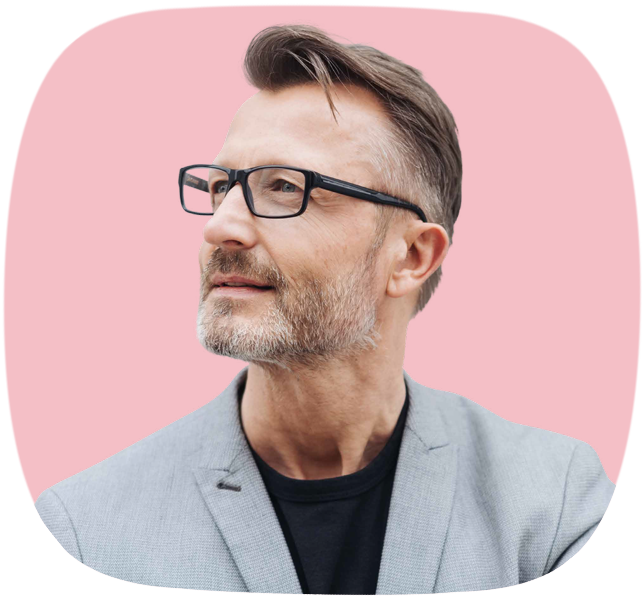 Das Seitenprofil eines lächelnden Mannes mit Brille, leicht grauen Haaren und Bart