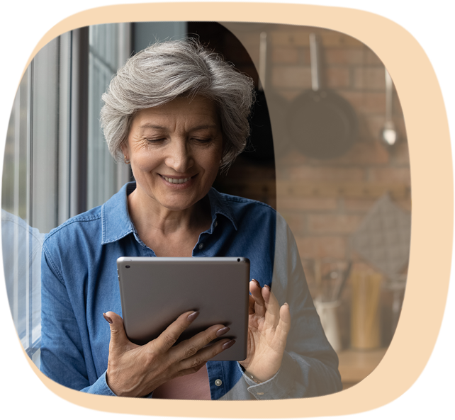 Eine Frau mit grauem Haar schaut etwas auf ihrem Tablet nach